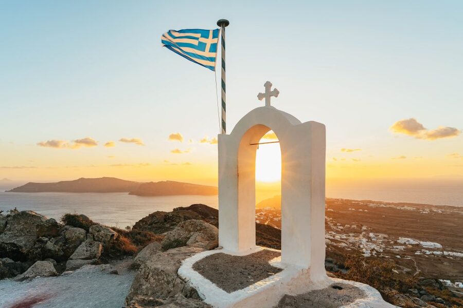A whitewashed chapel on the rim of the Santorini caldera at sunset