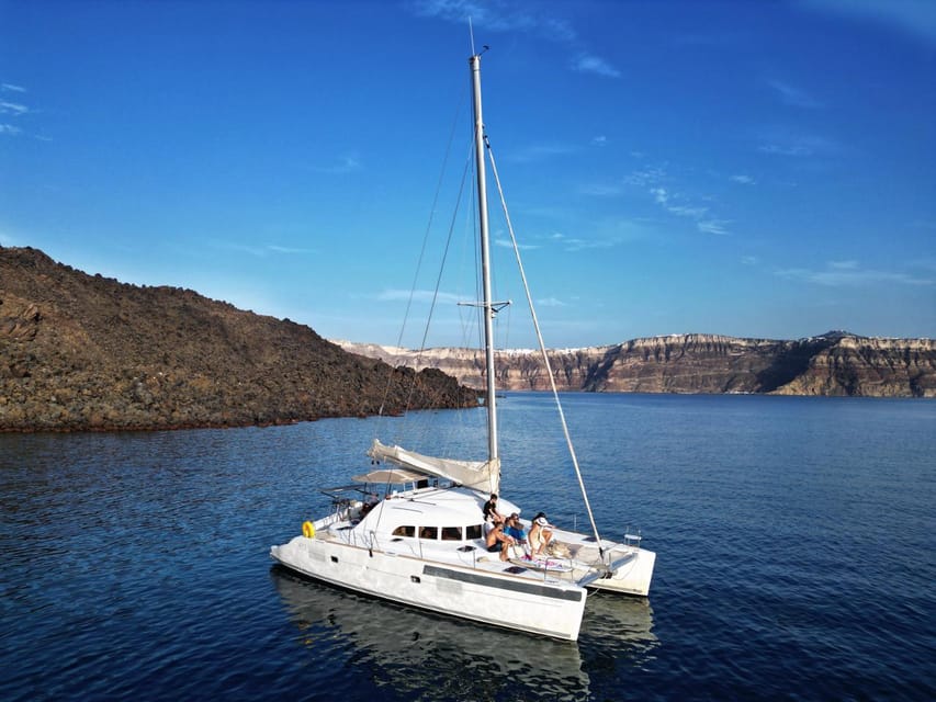 Santorini: Catamaran Cruise with Greek BBQ and Drinks - Sail-by views at Akrotiri: Indian Rocks and the Venetian Lighthouse
