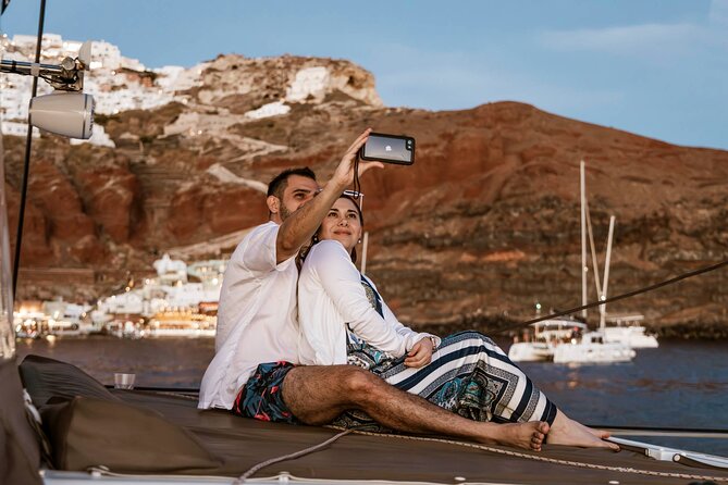Santorini Catamaran Cruise with Greek Meal, Open-Bar and Sunset - Caldera Views on the Move: Lighthouse, White Beach Area, and Clifftop Houses